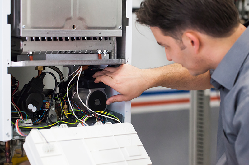4 Important Heat Pump Maintenance Tips. A maintenance man repairing a heat pump.