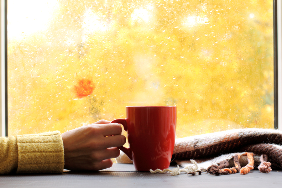 red mug of hot drink, when behind a window is rain in autumn in Boise