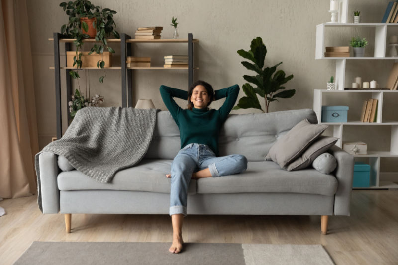 How a Whole-House Humidifier Keeps You Healthy. A woman relaxing on her couch.