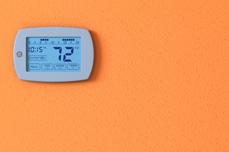 Thermostats 101. One orange wall with a digital thermostat panel.