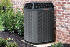 What’s That Smell Coming From My AC at Startup? Photo of an HVAC unit installed outside of a brick home or building.