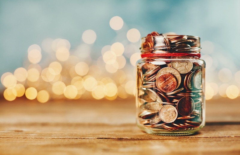 Saving money on heating bills by putting coins in a mason jar.